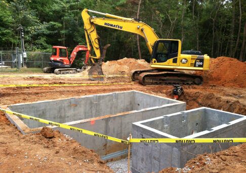 Twin poured concrete wet-wells on a Greenstone job site with heavy equipment